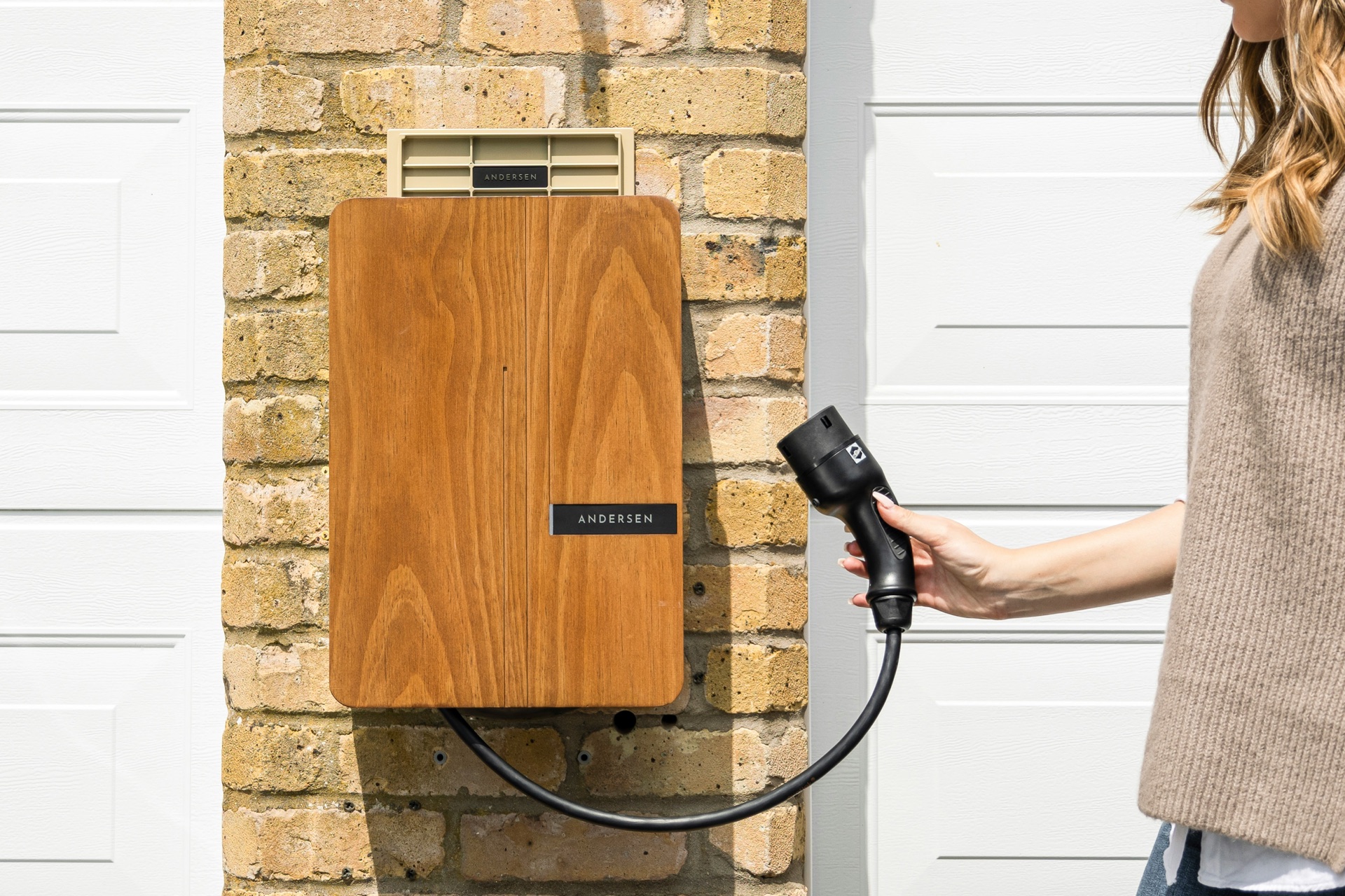Electric vehicle charging cable connected to a home EV charger on a driveway
