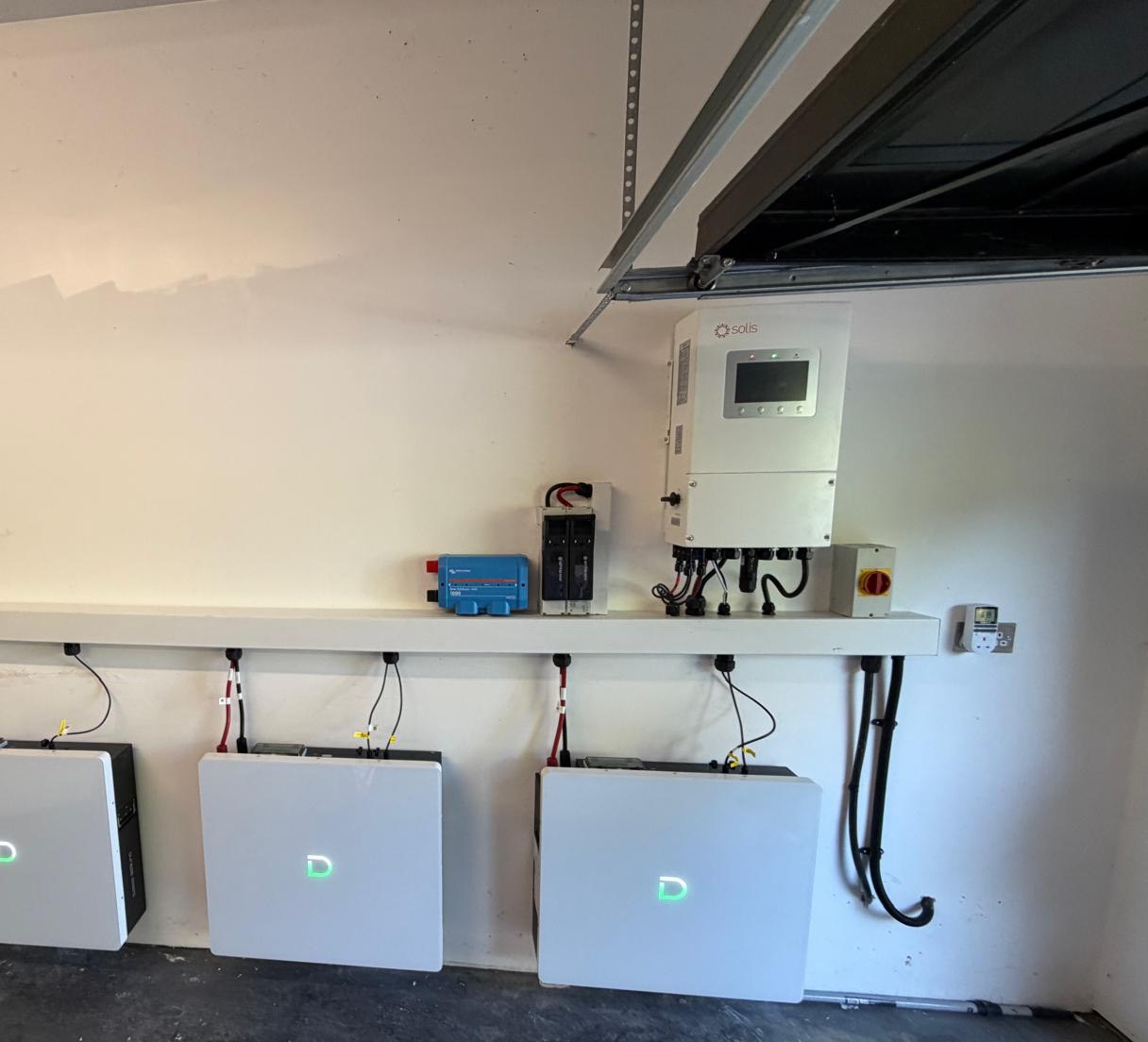 A Solis hybrid inverter and three Dyness battery units installed in a garage