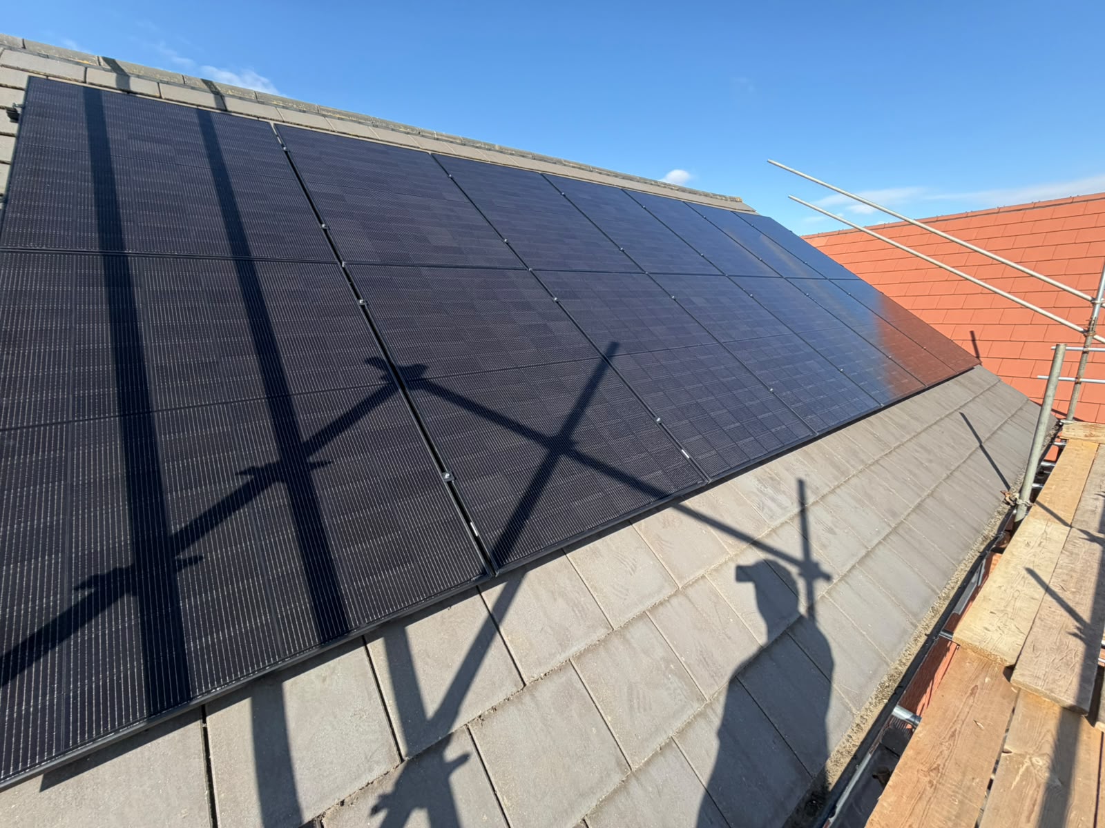 Solar panels on the front roof of a detached house, seen with scaffolding in place