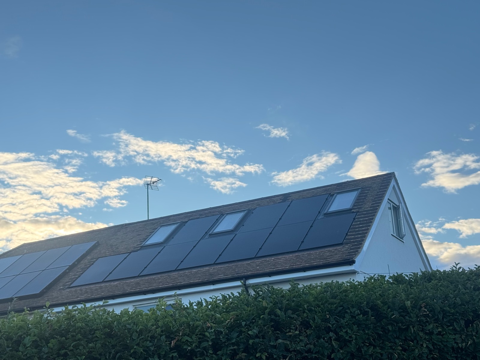 Black in-roof solar panels set flush into a tiled roof in Haversham, with two roof windows alongside