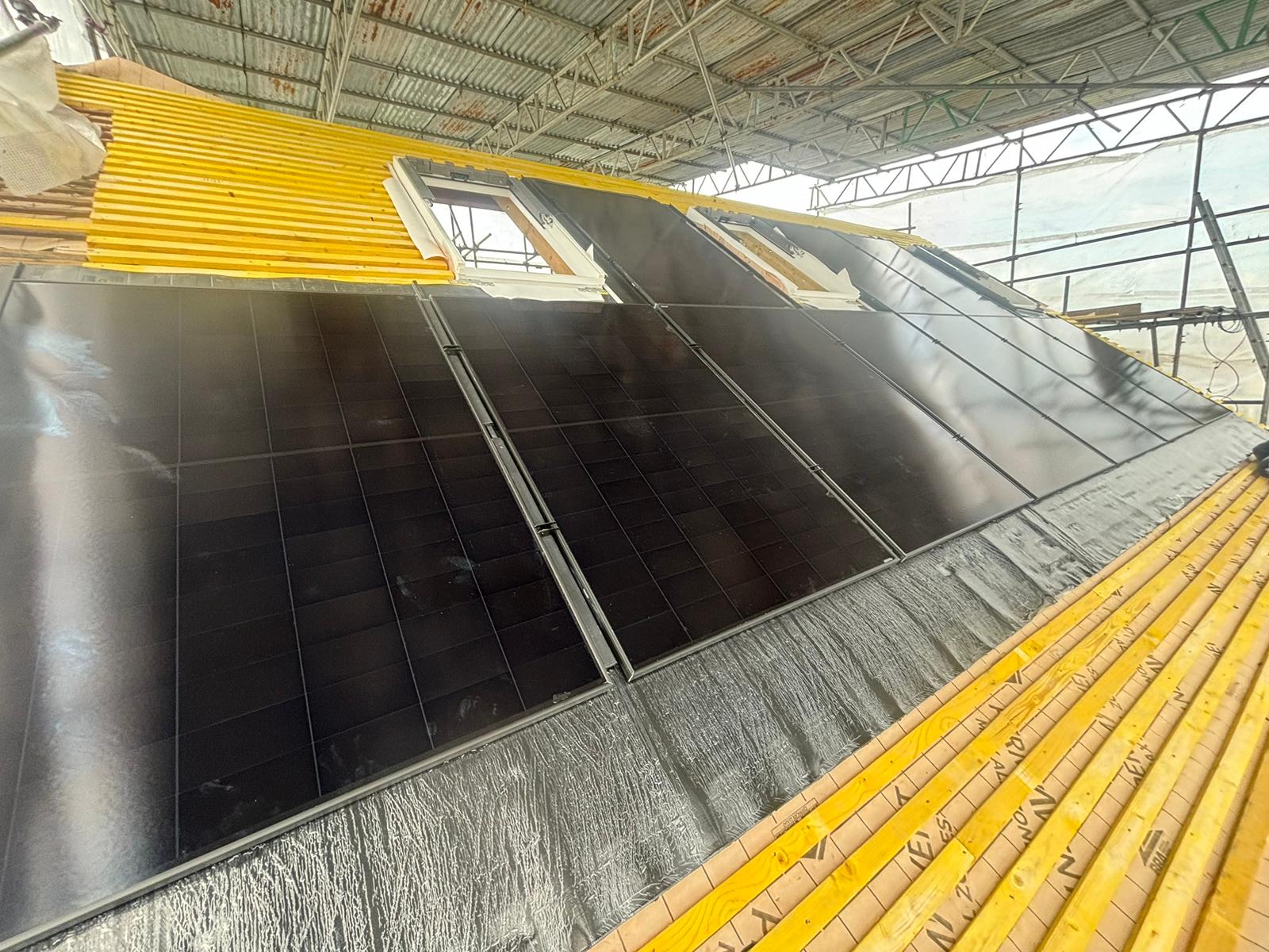 Black in-roof solar panels part-fitted on a tiled roof, with the GSE frames and flashing visible