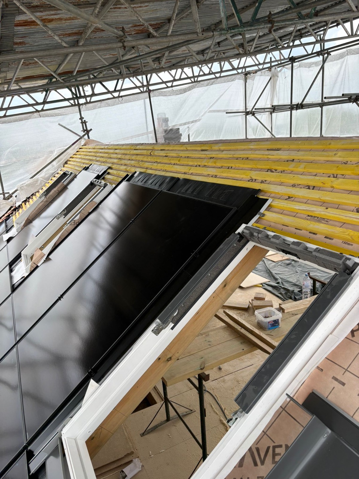 In-roof solar panels meeting the frame of a new roof window on a loft conversion