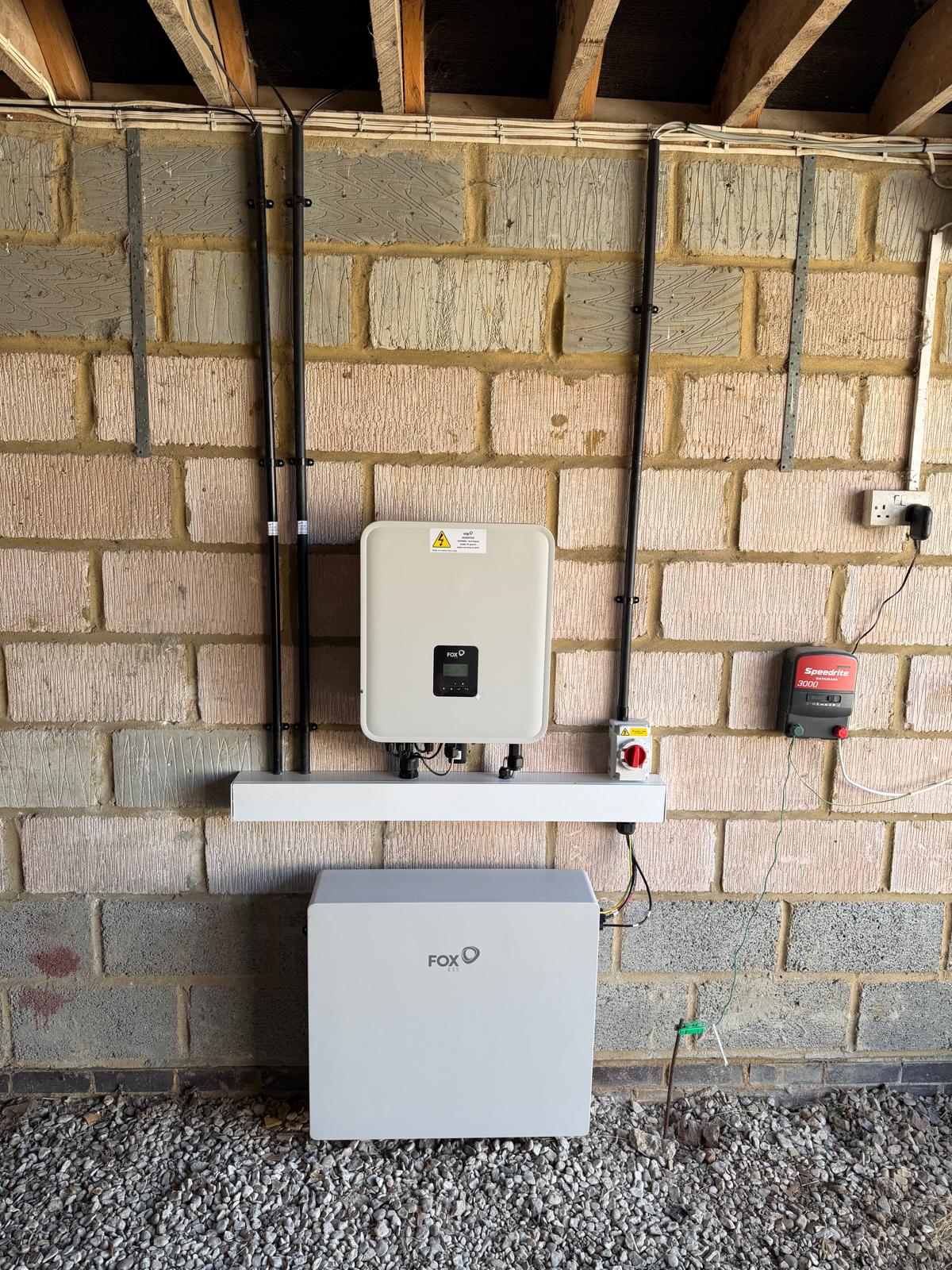 A Fox ESS hybrid inverter and battery mounted on a garage wall