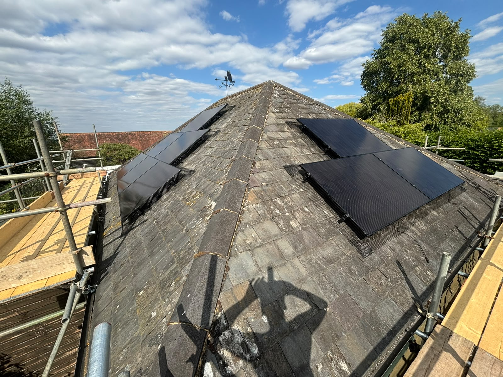 Black solar panels split across two pitches of a slate cottage roof in Little Kimble