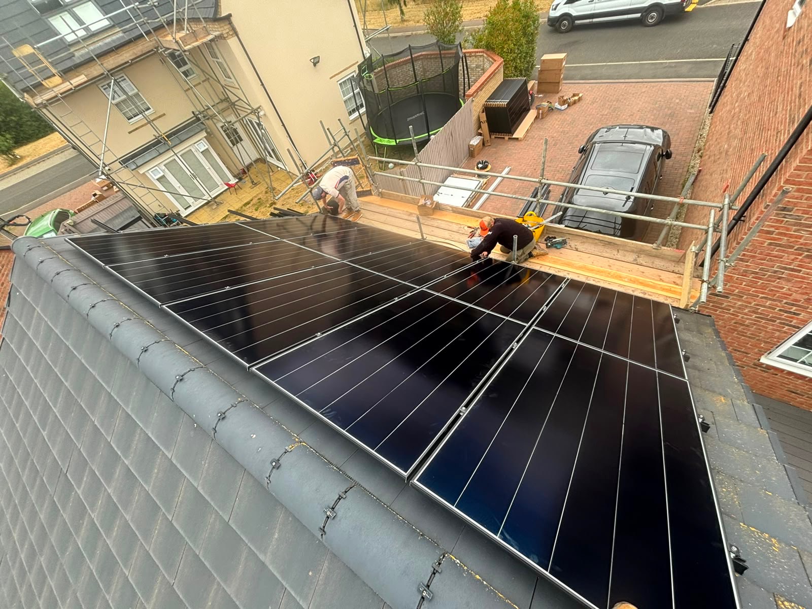 Installers fitting solar panels to a garage roof from a scaffold
