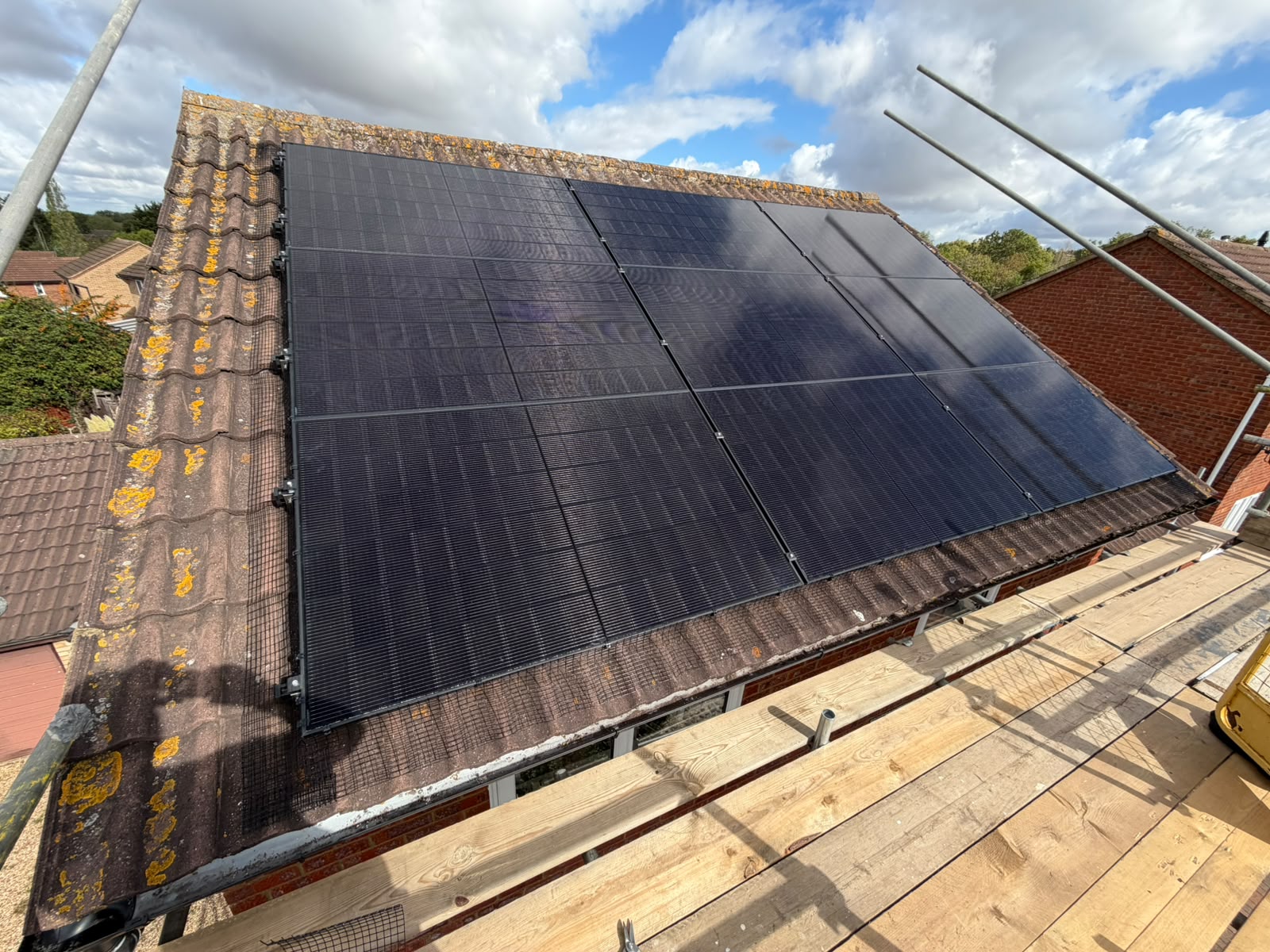 Black solar panels on the south-facing front roof of a small detached house in Milton Keynes