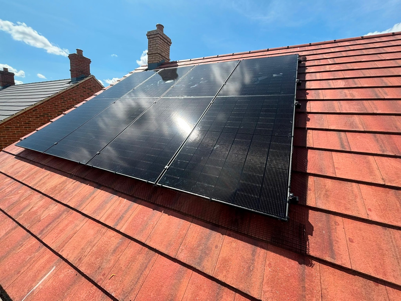 Black solar panels covering both faces of a tiled roof on a newer house in Quainton
