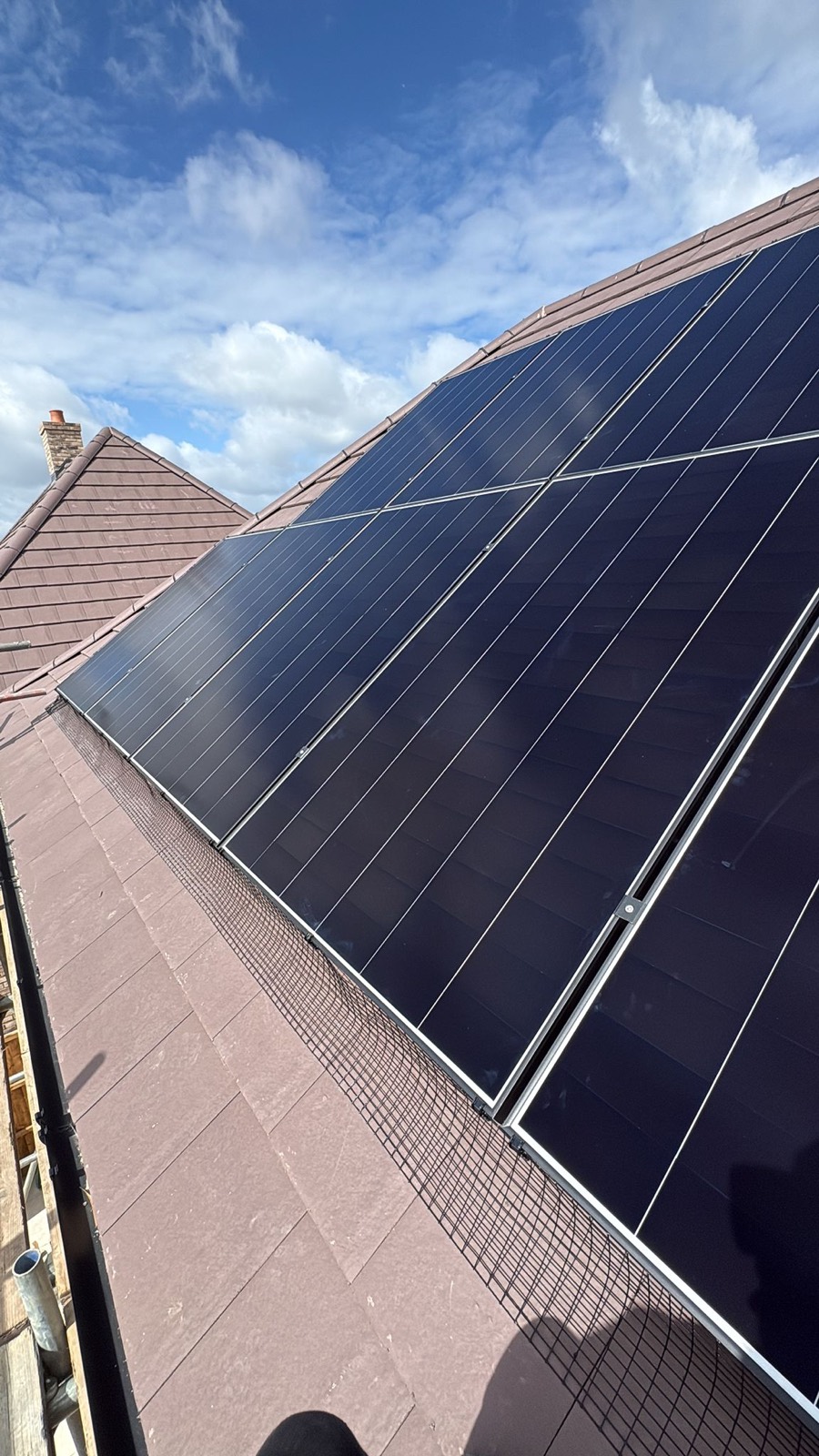 Solar panels on a tiled roof against a blue sky, seen from below
