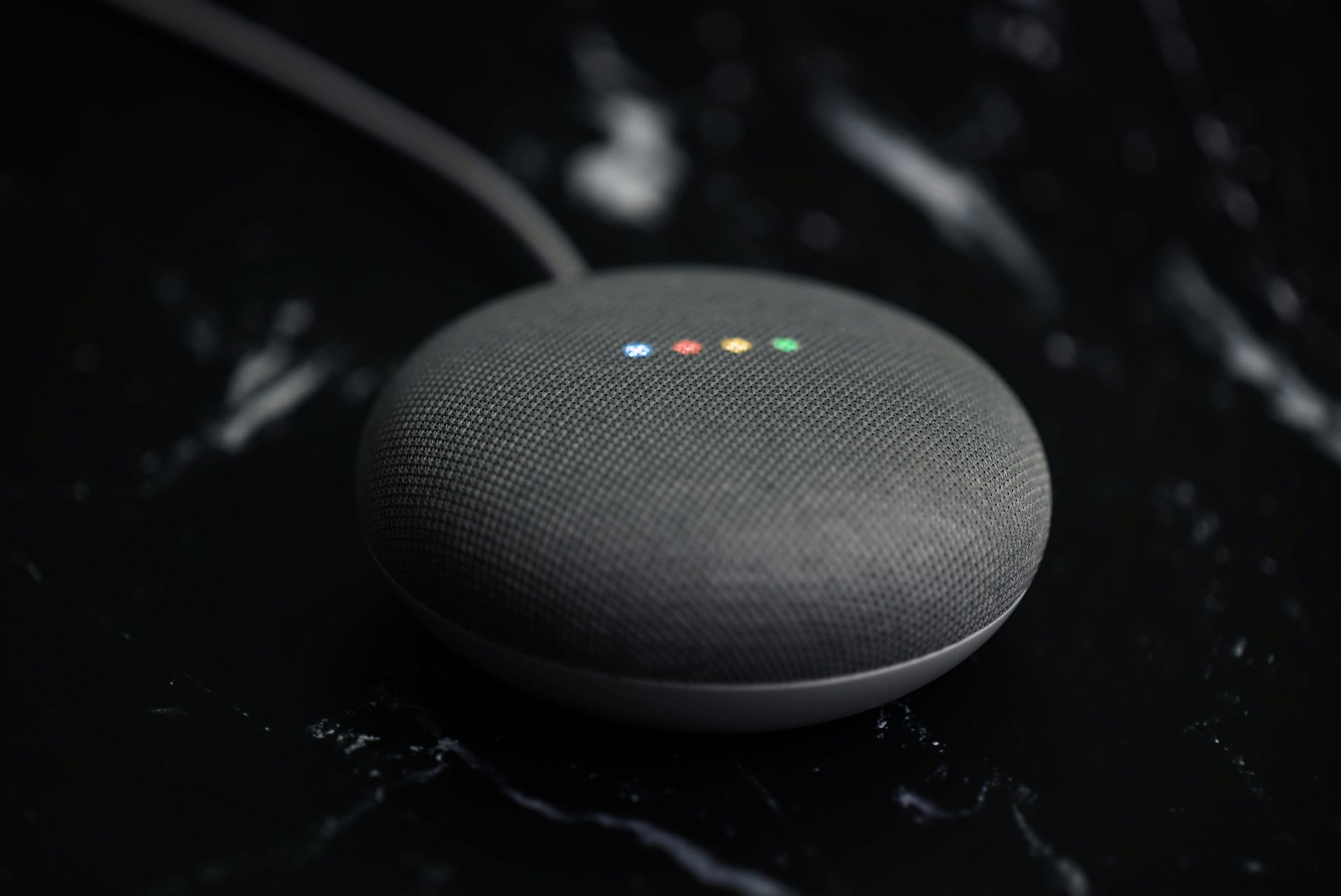 Google Nest Mini smart speaker on a black marble surface