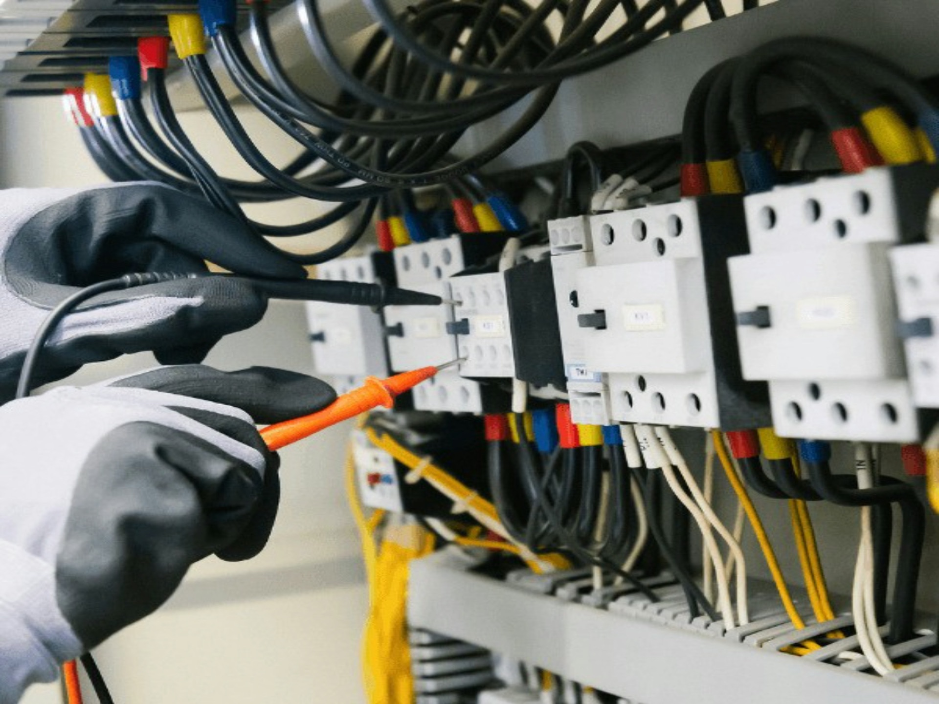 Electrician with test equipment at commercial distribution board