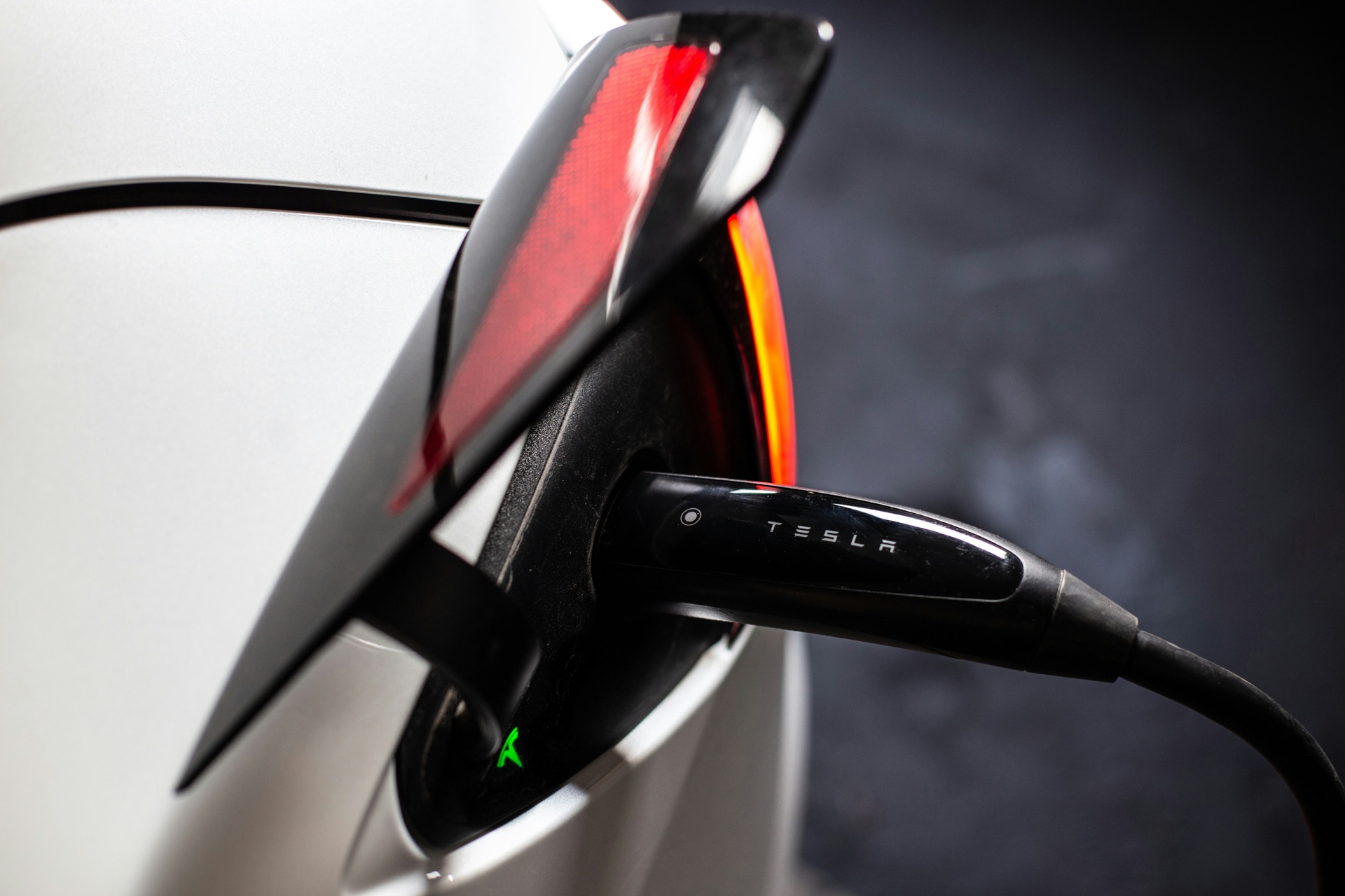 Tesla EV charging port close-up with connector plugged in