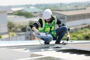 Solar panel installer installing solar panels on roof of warehouse