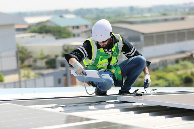 Solar panel installer installing solar panels on roof of warehouse